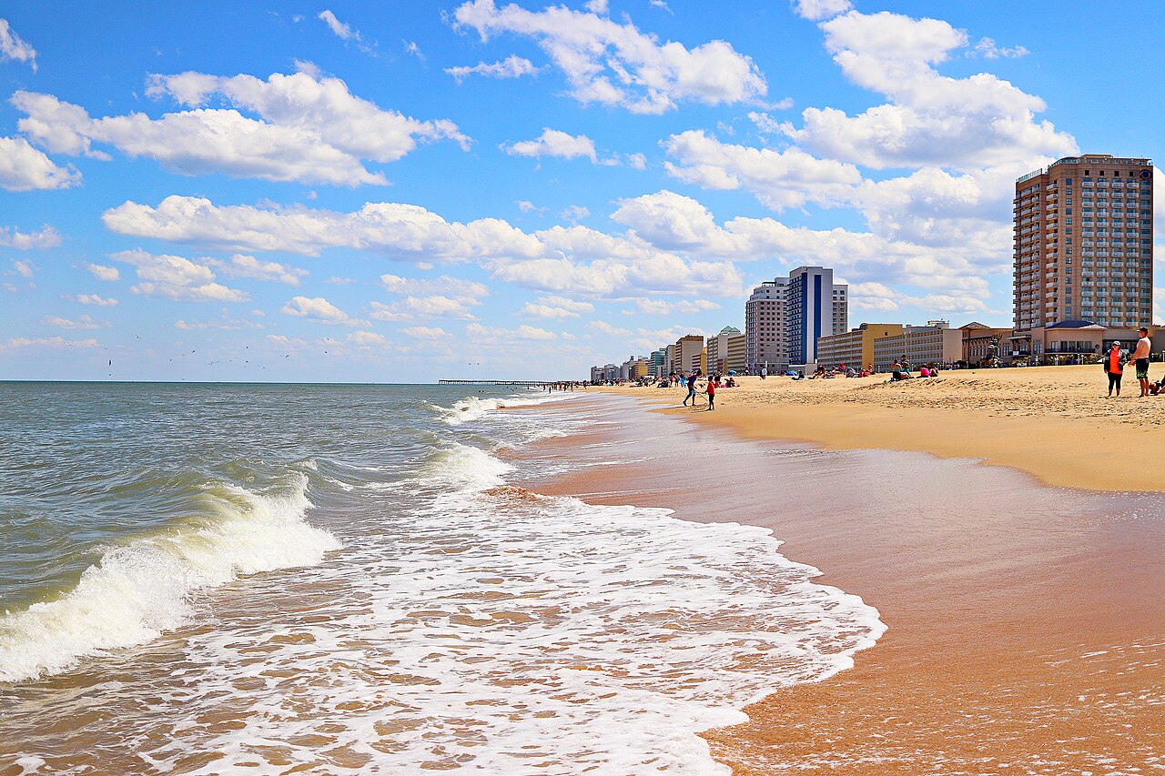 Waves reaching a sandy beach with hotels in the distance